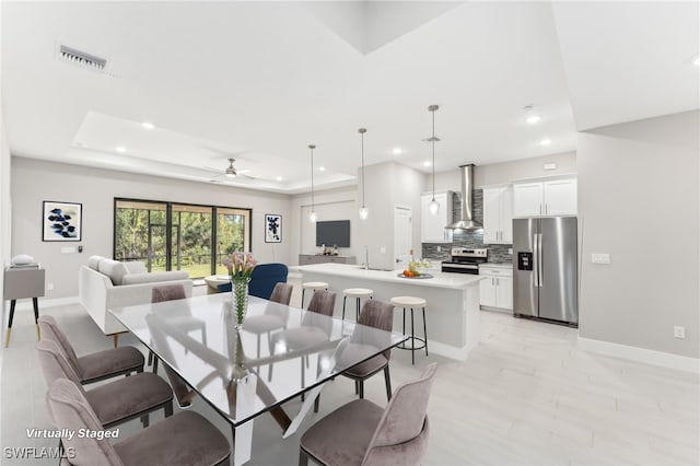 dining area featuring a raised ceiling and ceiling fan