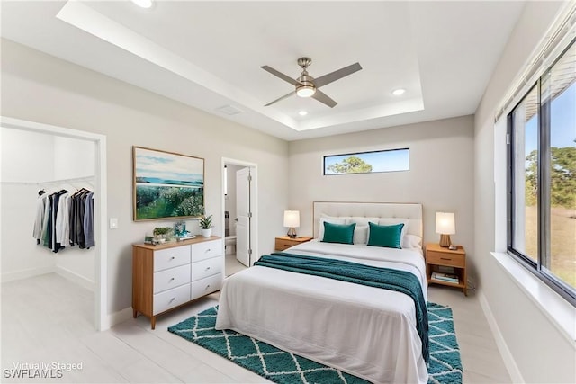 bedroom featuring ceiling fan, a closet, a raised ceiling, and multiple windows