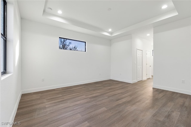 unfurnished room with a tray ceiling and dark hardwood / wood-style flooring