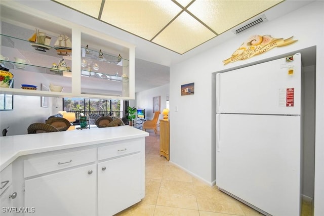 kitchen with white cabinets, white fridge, and light tile patterned flooring