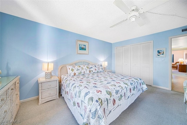 bedroom featuring ceiling fan, a closet, light carpet, and a textured ceiling