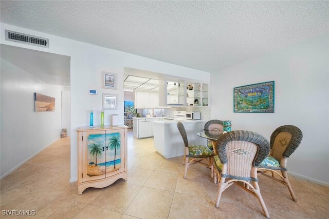 1440 Middle Gulf Dr Unit 2E, Sanibel, FL 33957 - dining area with a textured ceiling and light tile patterned flooring
