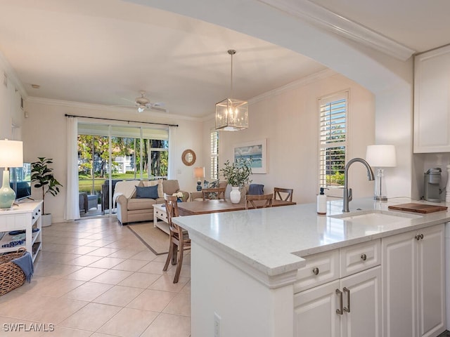 kitchen with sink, decorative light fixtures, white cabinets, ceiling fan with notable chandelier, and ornamental molding