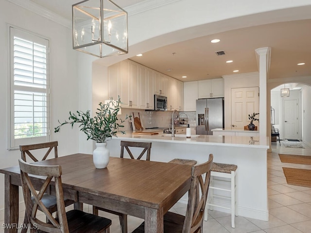 dining area with light tile patterned floors, ornamental molding, a healthy amount of sunlight, and a notable chandelier