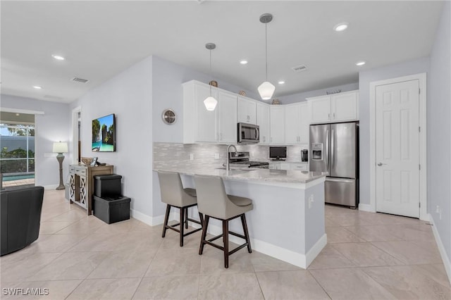 kitchen featuring backsplash, kitchen peninsula, appliances with stainless steel finishes, decorative light fixtures, and white cabinetry