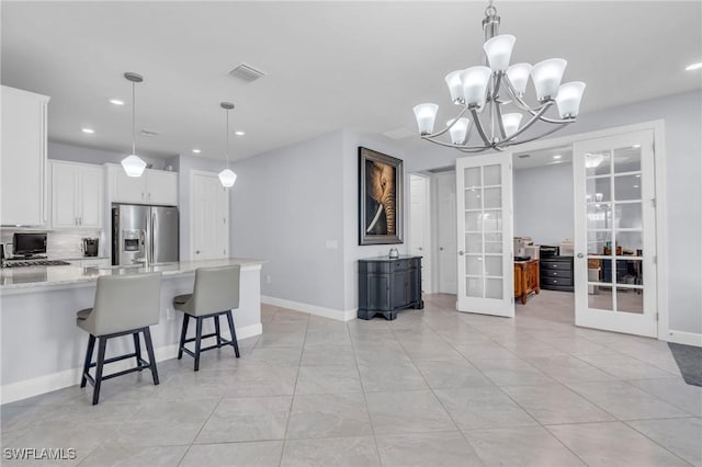 kitchen featuring stainless steel refrigerator with ice dispenser, white cabinetry, french doors, and pendant lighting