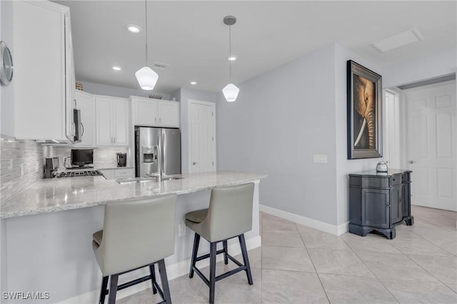 kitchen with light stone countertops, appliances with stainless steel finishes, backsplash, pendant lighting, and white cabinets