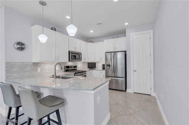 kitchen featuring white cabinetry, sink, stainless steel appliances, tasteful backsplash, and decorative light fixtures