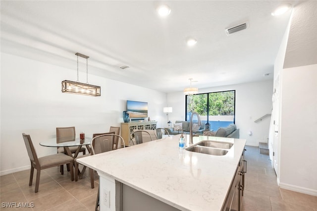 kitchen featuring pendant lighting, sink, and an island with sink