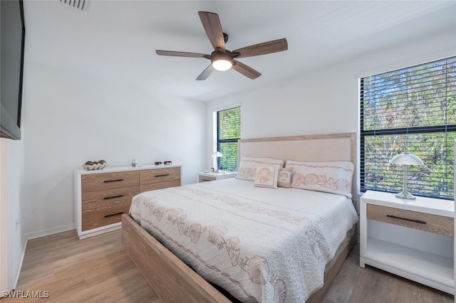 bedroom with multiple windows, ceiling fan, and light hardwood / wood-style flooring