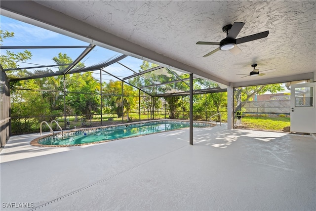 view of pool featuring glass enclosure, ceiling fan, and a patio area