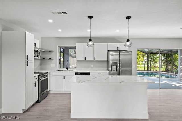 kitchen with stainless steel appliances, white cabinetry, hanging light fixtures, and a healthy amount of sunlight