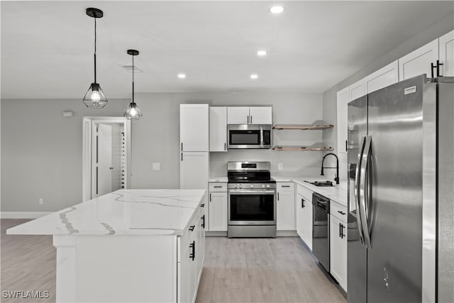 kitchen with appliances with stainless steel finishes, sink, pendant lighting, white cabinets, and a center island