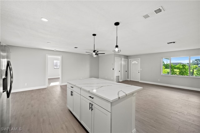 kitchen with stainless steel fridge with ice dispenser, white cabinets, light stone countertops, and light hardwood / wood-style floors