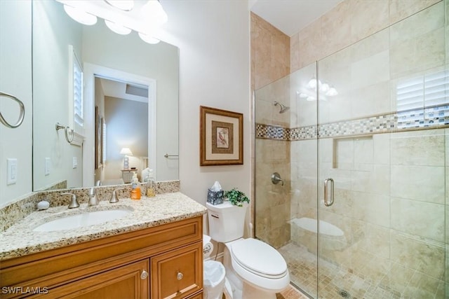 bathroom with vanity, toilet, and a shower with shower door