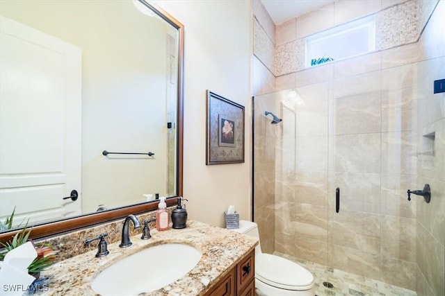 bathroom featuring vanity, a shower with shower door, and toilet