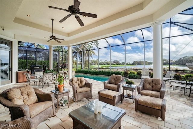 sunroom / solarium featuring a raised ceiling, ceiling fan, and plenty of natural light