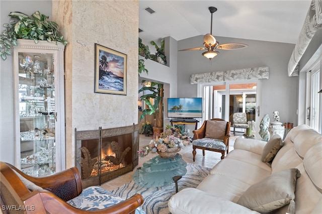 living room featuring ceiling fan, a fireplace, and vaulted ceiling