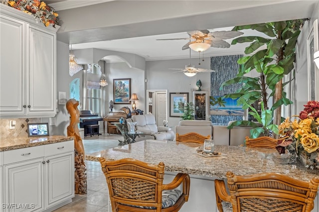 kitchen with tasteful backsplash, ceiling fan, white cabinets, and ornamental molding