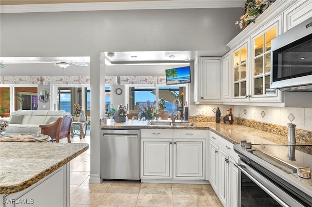 kitchen with appliances with stainless steel finishes, tasteful backsplash, sink, white cabinetry, and light tile patterned flooring