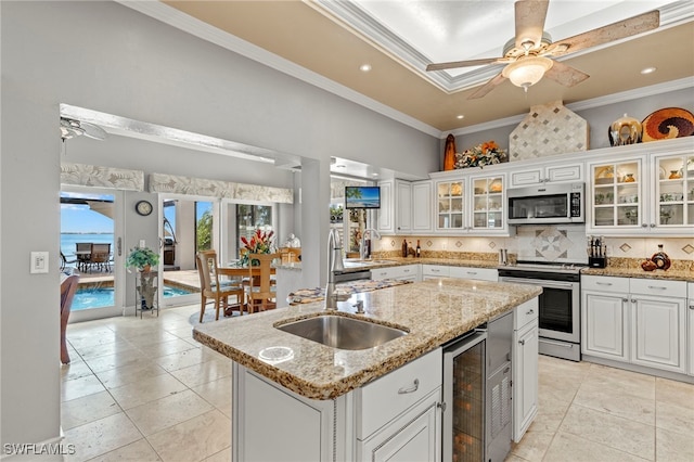 kitchen with appliances with stainless steel finishes, crown molding, sink, a center island with sink, and white cabinetry