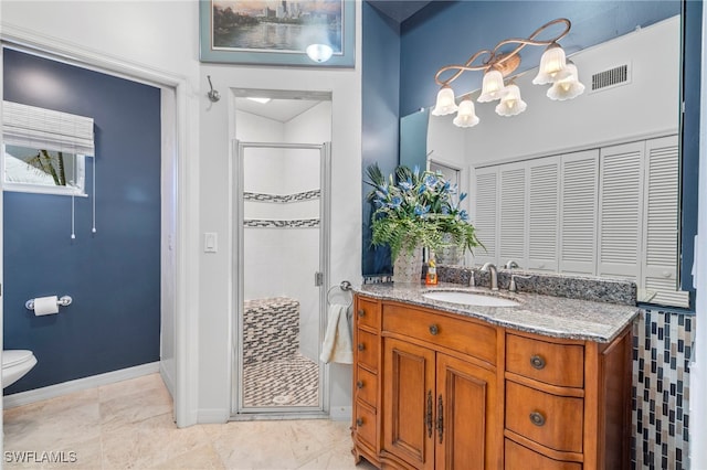 bathroom featuring vanity, toilet, and a shower with shower door