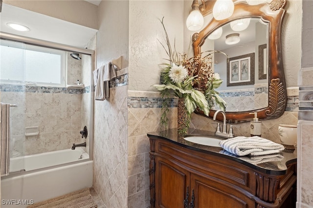 bathroom featuring tiled shower / bath combo, tile walls, and vanity