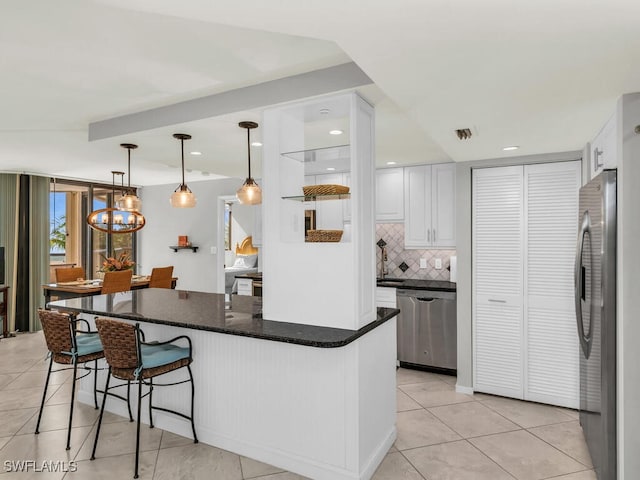 kitchen featuring white cabinets, pendant lighting, stainless steel appliances, and an inviting chandelier