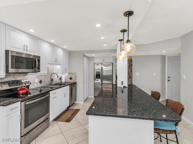 kitchen featuring pendant lighting, white cabinets, sink, appliances with stainless steel finishes, and a kitchen bar