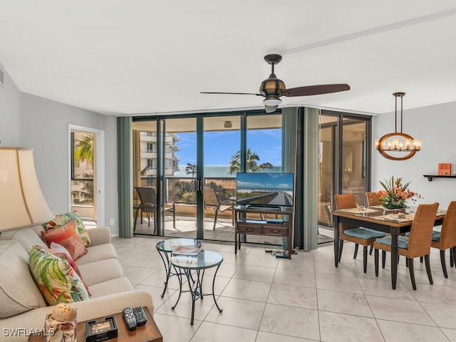 living room featuring light tile patterned floors, expansive windows, and ceiling fan with notable chandelier