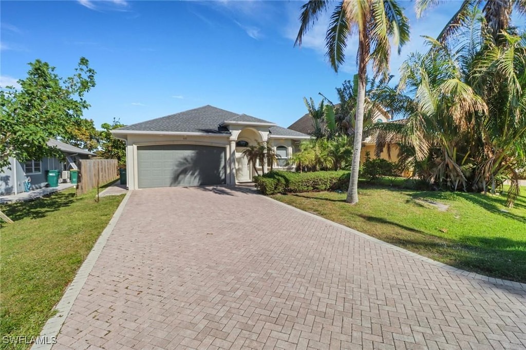 view of front of house with a front lawn, decorative driveway, fence, and an attached garage