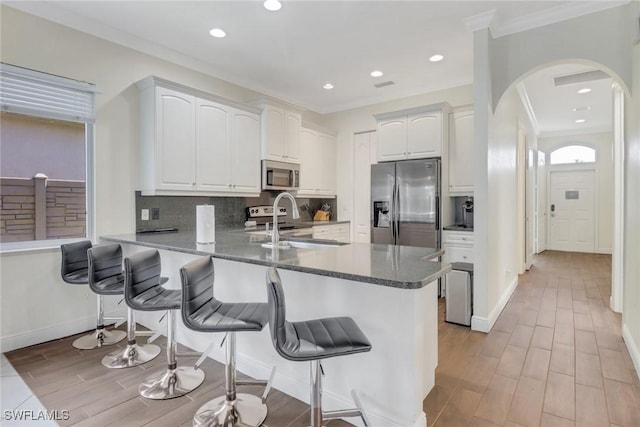 kitchen with stainless steel appliances, a peninsula, a sink, and white cabinetry