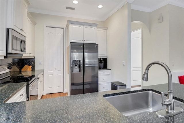 kitchen with a sink, visible vents, white cabinetry, appliances with stainless steel finishes, and crown molding