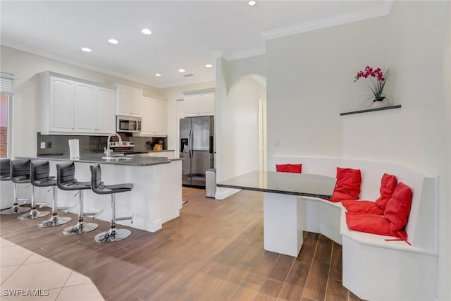 kitchen with dark countertops, stainless steel appliances, a peninsula, and white cabinetry