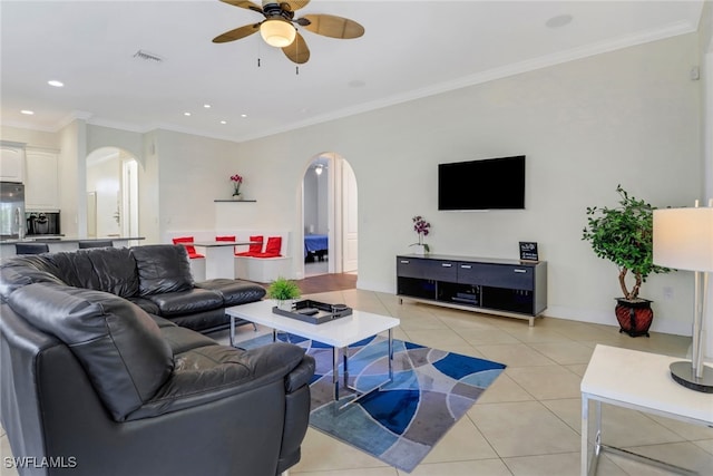 living area featuring arched walkways, visible vents, crown molding, and light tile patterned floors