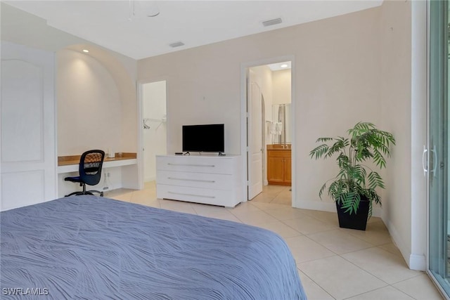 bedroom with visible vents, baseboards, ensuite bath, built in desk, and light tile patterned flooring