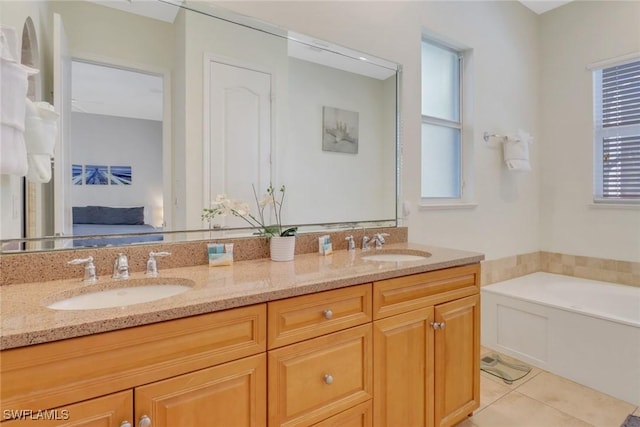 full bathroom featuring tile patterned flooring, a sink, a healthy amount of sunlight, double vanity, and ensuite bath