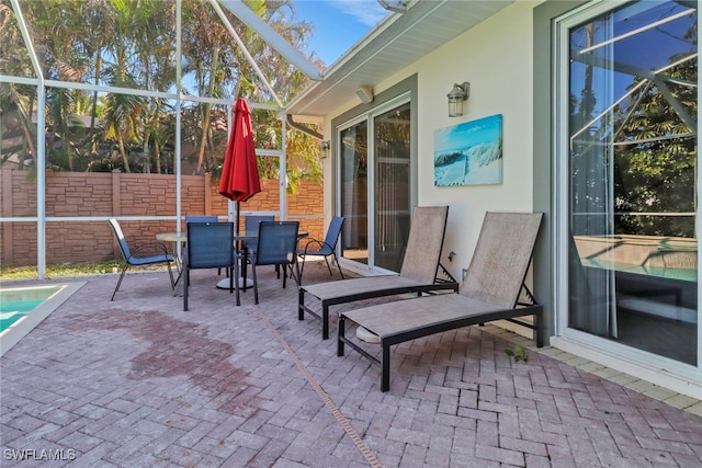 view of patio with outdoor dining space, a lanai, and fence