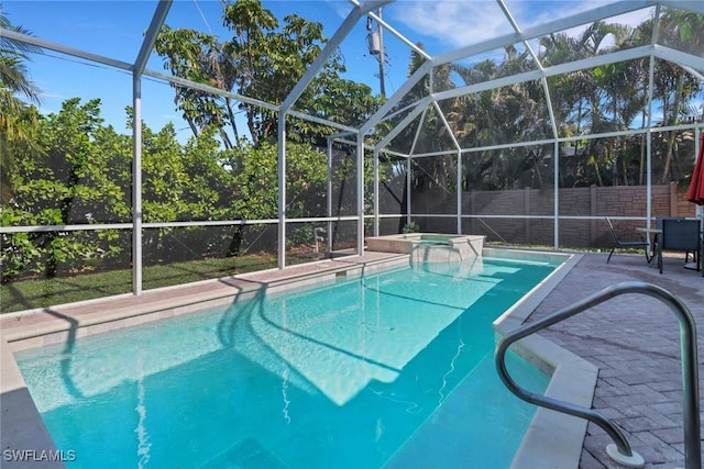 view of pool with a patio area, glass enclosure, a pool with connected hot tub, and a fenced backyard