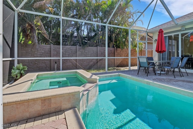 view of swimming pool featuring glass enclosure, a patio, a fenced backyard, and a pool with connected hot tub