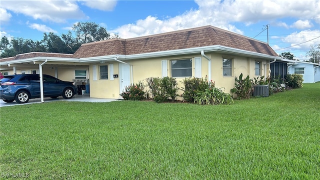 ranch-style home featuring central AC unit, a front yard, and a carport