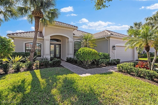 mediterranean / spanish home featuring a front yard, french doors, and a garage