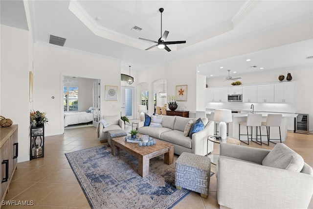 living room with light tile patterned floors, wine cooler, ceiling fan, and crown molding