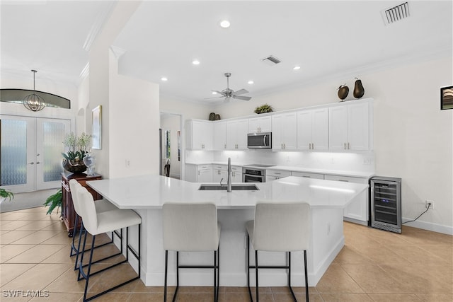 kitchen with french doors, white cabinets, beverage cooler, and appliances with stainless steel finishes