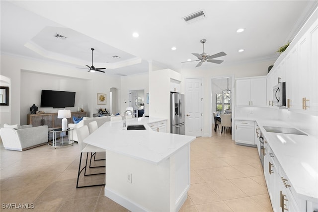 kitchen with stainless steel appliances, ceiling fan, sink, white cabinets, and a large island