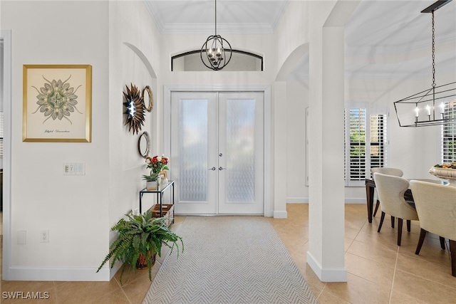 tiled foyer entrance featuring french doors, an inviting chandelier, and crown molding