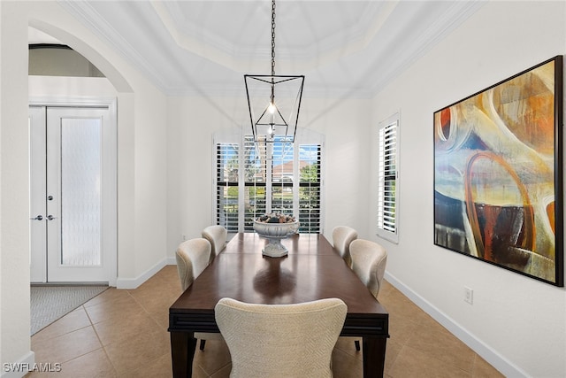 dining area with a tray ceiling, crown molding, and light tile patterned floors