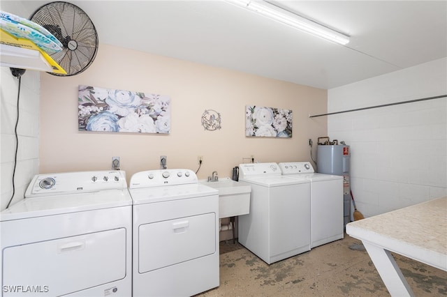 clothes washing area featuring water heater, laundry area, a sink, and washing machine and dryer