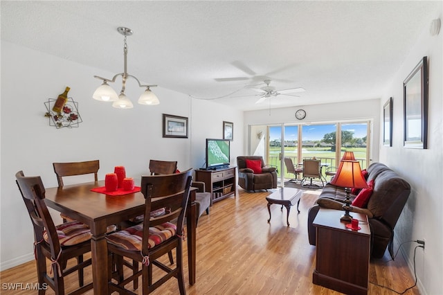 dining room featuring baseboards, light wood finished floors, and ceiling fan with notable chandelier