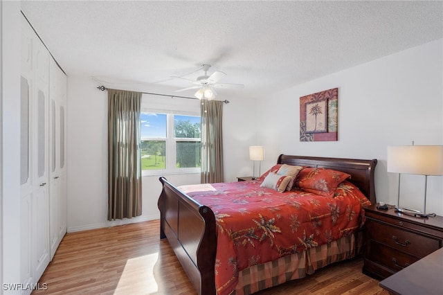 bedroom with light wood finished floors, baseboards, a ceiling fan, a textured ceiling, and a closet